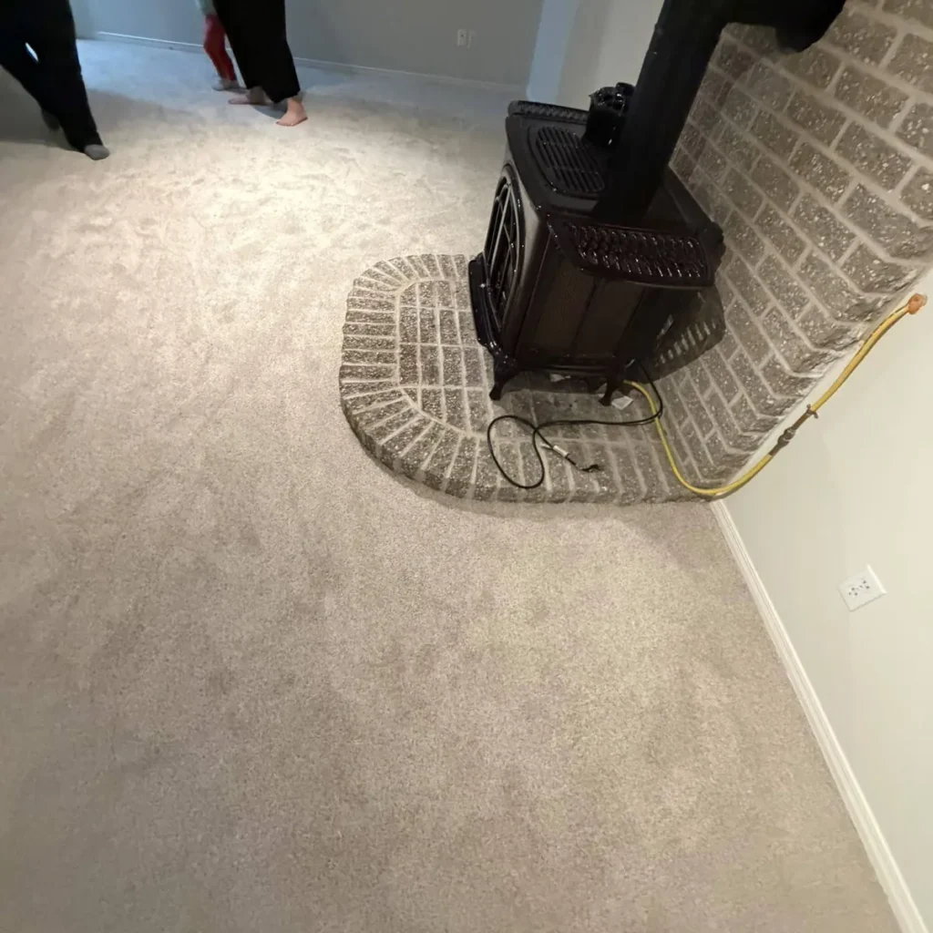 Light grey carpet fitted around a wood stove on a curved brick hearth