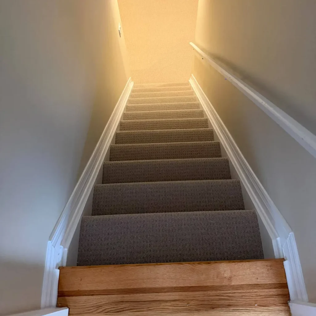 Enclosed staircase in grey patterned carpet with an oak landing