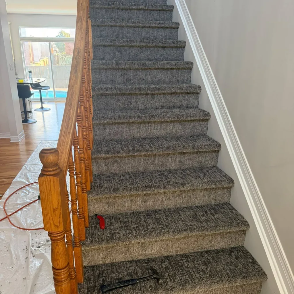 Straight staircase in grey textured carpet with an oak handrail