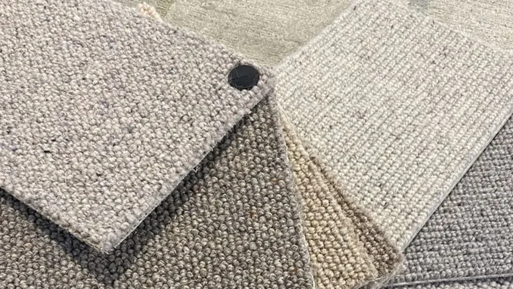 Berber loop carpet samples in grey, beige and cream fanned out for choosing at home