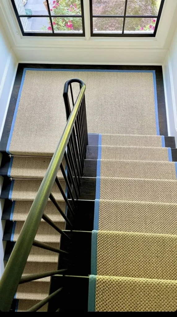 Natural-tone stair runner with blue binding on black-painted stairs on Wolfe Island